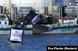 Campanii de greenwashing desfășoară până și companiile petroliere. Protest Greenpeace împotriva publicității înșelătoare de la Shell în portul Rotterdam, 4 octombrie 2021.