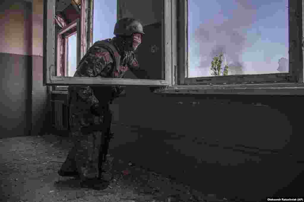 Një ushtar ukrainas shikon betejën që po zhvillohet poshtë tij në qytetin Severodonjeck.