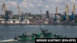  O navă a Marinei Ruse trece pe lângă portul maritim de marfă Mariupol, un oraș ucrainean ocupat de pe Marea Azov, în iunie 2022.