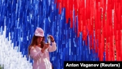 A woman takes a photo of an installation made in the colors of the Russian national flag at a Russia Day celebration in St. Petersburg on June 12.