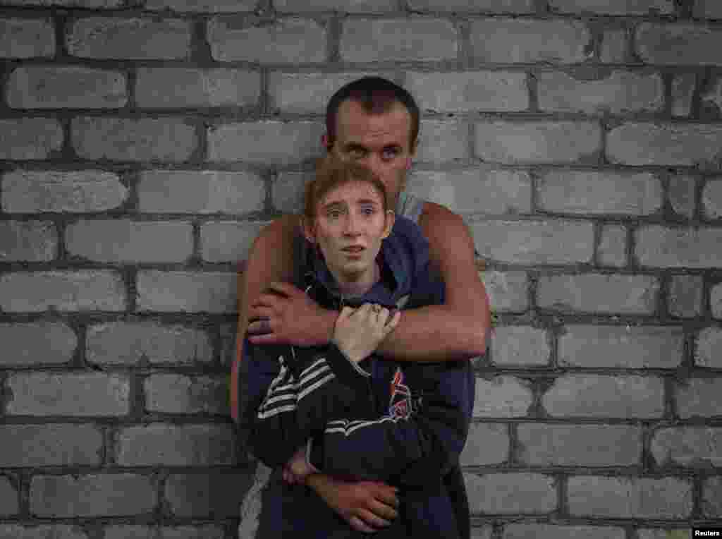 Članovi porodice posmatraju kako spasioci rade dok čekaju vesti o njihovim rođacima koji se nalaze pod ruševinama stambene zgrade oštećene ruskim vojnim udarom u gradu Časiv Jar, u Donjeckoj oblasti, 10. jula 2022. &nbsp;