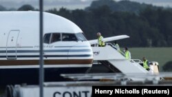 Članovi osoblja ukrcavaju se u avion koji je, porema objaviama medija, prvi trebao da oreveze migrante nazad u Ruand iz Britanije, u junu 2022.