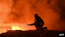 Një zjarrfikës përpiqet ta shuajë zjarrin në vendin e një sulmi me dron natën mes 23 dhe 24 shtatorit në Harkiv, Ukrainë.