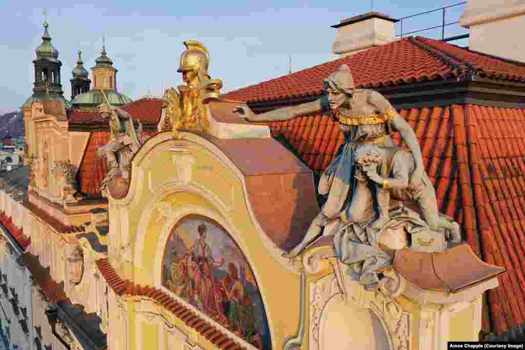 Druga figura na krovu starog Praškog osiguravajućeg društva nazvana &quot;poziv na uzbunu&quot; prikazuje ženu i dete kako upozoravaju ljude na požar. Skulptura je bila nedovršena kada je umro njen tvorac Bohuslav Šnirh, a dovršio ju je njegov pripravnik Ladislav Saloun. &nbsp;