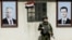 Руски военен стои между портретите на сирийския президент Башар ал-Асад (вдясно) и на руския президент Владимир Путин на контролно-пропускателен пункт в покрайнините на Дамаск, 1 март 2018 г.