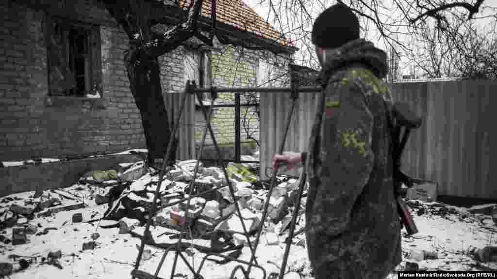 Порожня гойдалка Стахановця. Солдат Збройних сил України гойдає порожнє місце. Якщо розвернутися, то на горизонті видніються укріпрайони бойовиків. Навколо качелі – понівечені або й вщент зруйновані будівлі