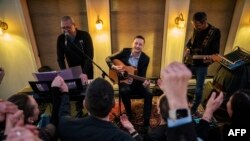 Marele învingător al alegerilor, Jens-Frederik Nielsen (în centru), cântând la chitară la o cafenea din Nuuk pe 11 martie 2025.