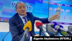 Глава Минздрава Алымкадыр Бейшеналиев на пресс-конференции демонстрирует бутылку с отваром иссык-кульского корня. Бишкек. 16 апреля 2021 года.