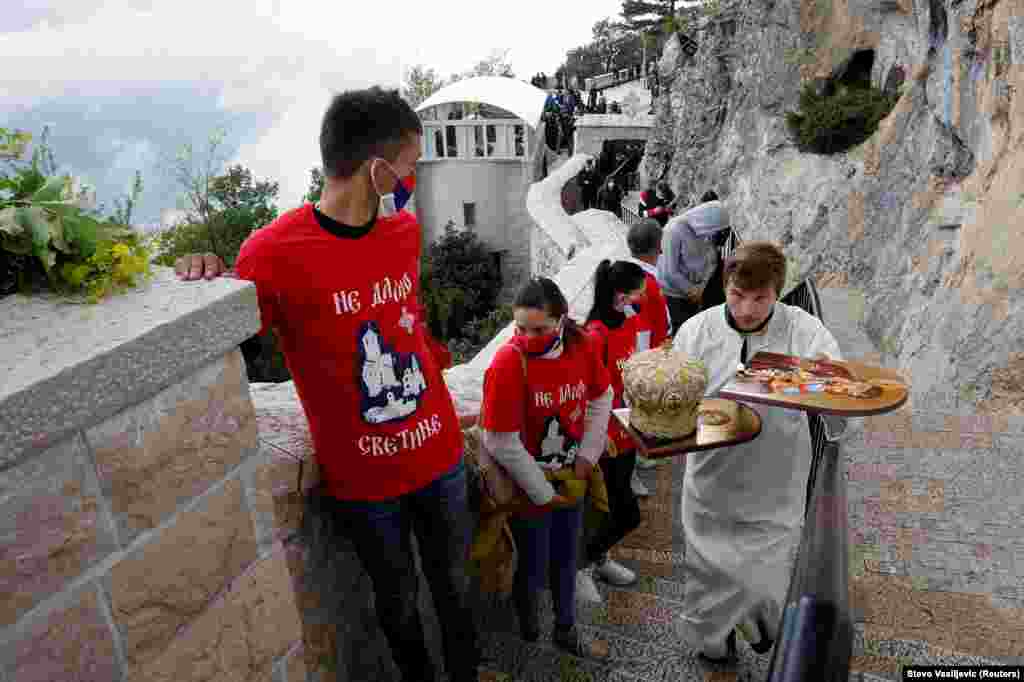 Sveštenik prolazi pored vernika sa zaštitnim maskama ispred Crkve Svetog Vasilija Ostroškog u Nikšiću u Crnoj Gori, 12. maj 2020. godine.&nbsp;
