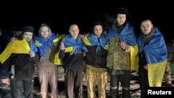 Току що освободени украински военнопленници позират със знамена на родината си, 3 януари 2023 г.