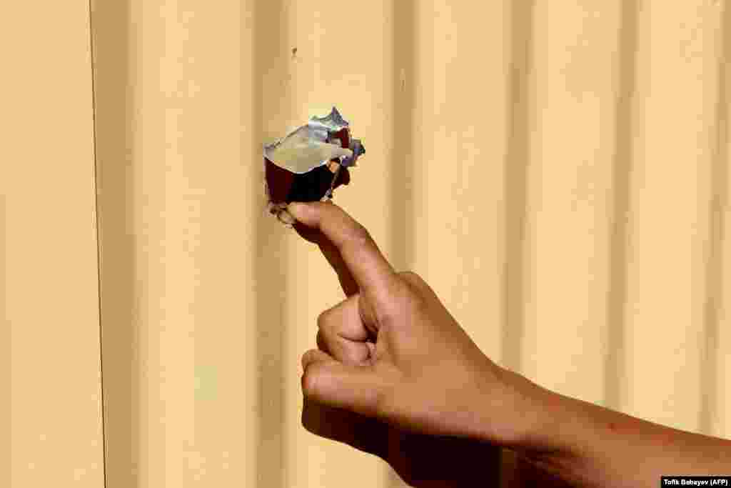 Dječak stoji uz kapiju kuće u selu Agdam u azerbejdžanskom okrugu Tovuz koja je oštećena granatiranjem 15. jula.