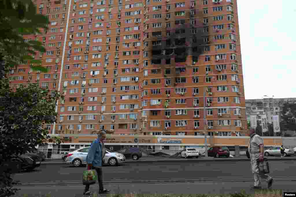 Жители идут перед многоквартирным домом, пострадавшим от удара российского беспилотника, Одесса, Украина, 28 июня 2025 года. REUTERS/Нина Ляшонок