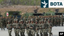 Ushtarët kinezë vrapojnë ndërsa ushtarët kamboxhianë shikojnë gjatë një stërvitje të përbashkët ushtarake në vitin 2024.