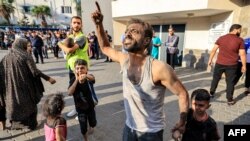 Un bărbat palestinian ține de mână un copil în timp ce gesticulează în fața spitalului al-Shifa din orașul Gaza, pe 12 octombrie 2023. Luptele violente dintre Israel și mișcarea Hamas continuă pentru a șasea zi consecutivă.