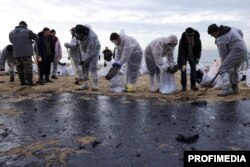 Munictorii curăță nisipul îmbibat cu petrol în stațiunea Anapa de la Marea Neagră, după ce petrolierele Volgoneft 212 și Volgoneft 239, încărcate cu 9.200 de tone de păcură, au naufragiat în strâmtoarea Kerci - decembrie 2024.