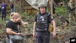 A woman cries as police officers inspect the site of a Russian missile attack that hit a recreation area killing five and injuring 16 on the outskirts of Kharkiv, Ukraine, on May 19.