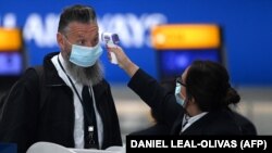 Az utasok hőmérsékletét megmérik, amikor bejelentkeznek a nyugat-londoni Heathrow repülőtérre, 2021. április 29-én