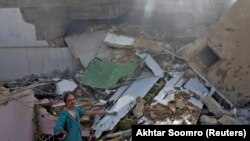 A man stands on the debris of a house at the site of a passenger plane crash in a residential area near an airport in Karachi on May 22.