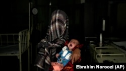 Nazia 30, e cila ka humbur katër fëmijë për shkak të kequshqyerjes së rëndë, mban fëmijën e saj të kequshqyer në një spital në provincën Parwan në veri të Kabulit, Afganistan më 2022.