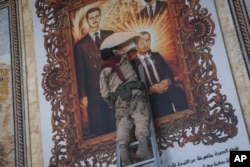 Një rebel duke grisur portretin e Bashar al-Assadit dhe të babait të tij, Hazef Assad. Alepo, 2 dhjetor 2024.