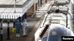 Экспэрты-крыміналісты ідуць побач зь цягніком, у якім адбыліся нажавыя напады, 2 лістапада 2025 году