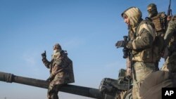 Sirijski pobunjenici stoje zaplijenjenom oklopnom vozilu sirijske vojske u predgrađu Hame, Sirija, 3. decembra 2024.