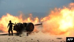 An Afghan National Army soldier fires an artillery shell during ongoing clashes between Afghan security forces and suspected Islamic State (IS) militants in Kot District on June 26.