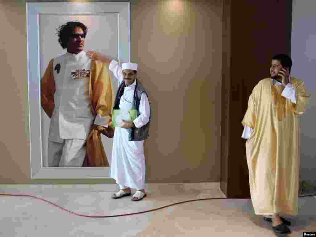 Libijac se fotografiše pored portreta Moamara Gadafija, Tripoli, juli 2011.
