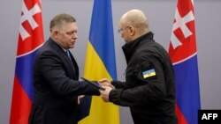 Денис Шмихал (вдясно) и словашкият му колега Роберт Фицо си разменят папки с подписани документи по време на срещата си в Ужгород. 