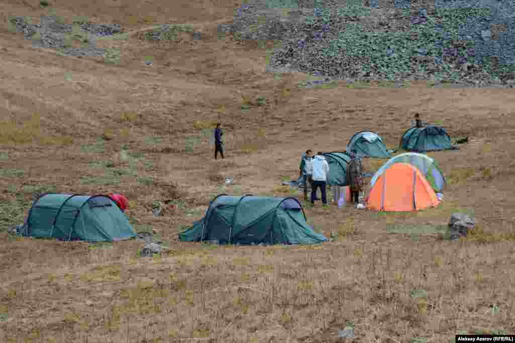 На этом фото &ndash; палаточный лагерь участников Beken Ata Expeditions: Sacred QyzEmshek. Рядом с лагерем протекает ручей, который едва просматривается под густо поросшей вдоль него травой. Считается, что именно наличие здесь воды привлекает диких животных. А вслед за ними сюда шли люди древних эпох, чей быт и чью культуру наши современники пытаются реконструировать. Высота над уровнем &ndash; моря 3000&ndash;3100 метров. Хотя это место считается относительно защищенным от сильных ветров, условия для проживания здесь довольно суровые. Ночью в емкостях с водой образовывались куски льда. Несколько раз местность и лагерь накрывало дождем или мокрым снегом. В первый день участники экспедиции археологией не занимались. Они осваивались, привыкали к месту временного пребывания.
