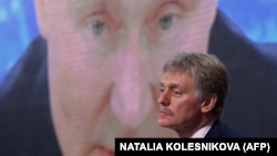 Говорителят на Кремъл Дмитрий Песков седи пред екран, излъчващ годишната пресконференция на руския президент Владимир Путин, 17 декември 2020 г.