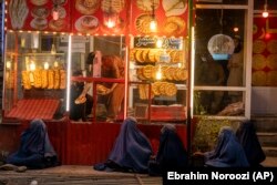 Femei afgane, așteaptă să primească pomană în fața unei brutării din provincia Parwan, la nord de Kabul, Afganistan, mai 2022.