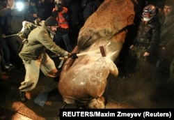 Egy ukrán férfi, egy kalapács és egy Lenin-szobor 2013-ban Kijevben