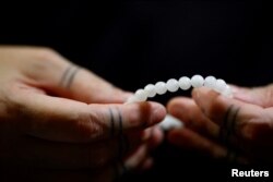 Brățară din criolit, o piatră rară groenlandeză, în mâinile artizanei Nadja Arnaaraq Kreutzmann la Nuuk, pe 12 februarie 2025.