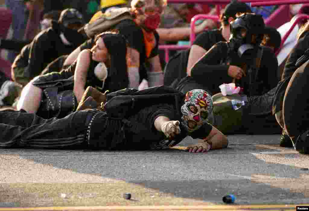 Демонстранты укрываются во время акции протеста против федеральных иммиграционных проверок в центре Лос-Анджелеса, Калифорния, США, 8 июня 2025 года. REUTERS/David Ryder