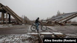 Mještanin vozi bicikl u blizini uništenog mosta u gradu Pokrovsk, u blizini linije fronta u regiji Donjeck, Ukrajina 19. 12. 2024. 
