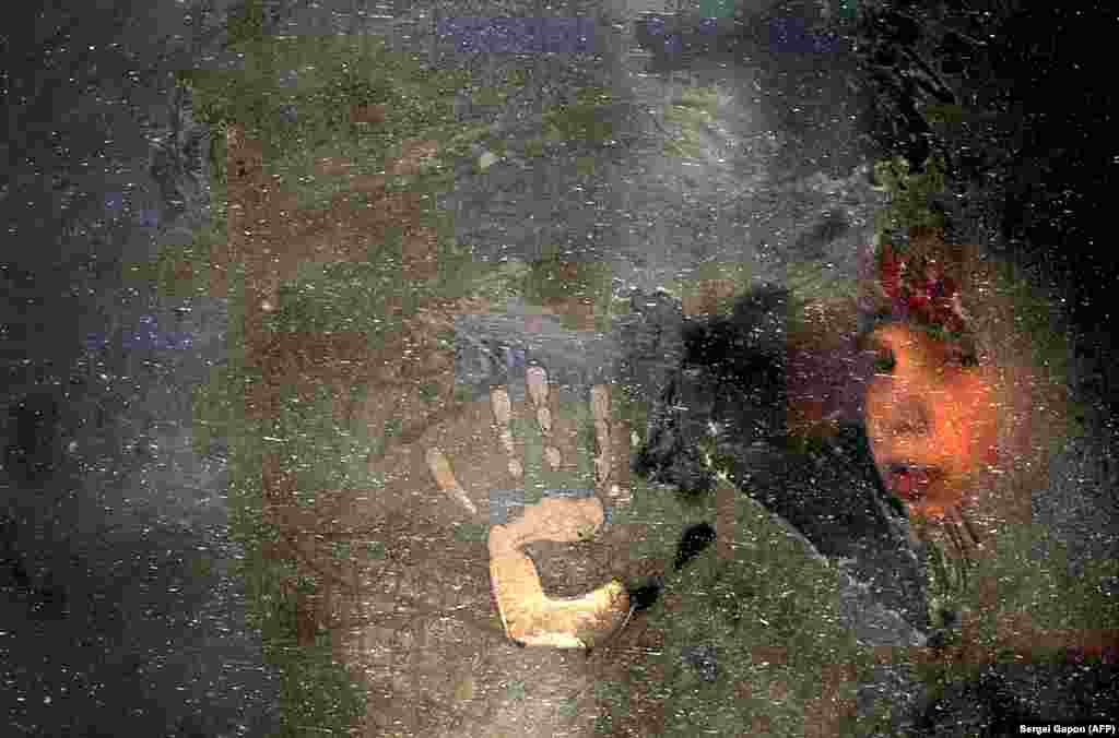 Момче гледа низ замрзнат прозорец на автобус, Минск, Белорусија, 05.01.2016.