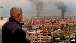 Мъж гледа към южните части на Бейрут, от които се издига дим след израелски ракетни удари, 6 октомври 2024 г.