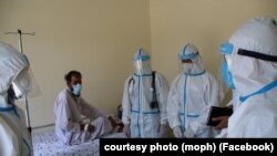 FILE: Healthcare workers treat a person infected with the coronavirus in the eastern Afghan province of Laghman in June.