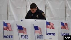 Сотрудник полиции готовится голосовать на участке в здании школы в Нью-Гэмпшире, США. 9 февраля 2016 года.