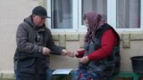 Un poștaș îi oferă pensia unei bătrâne din satul Iepureni, comuna Cania, raionul Cantemir.