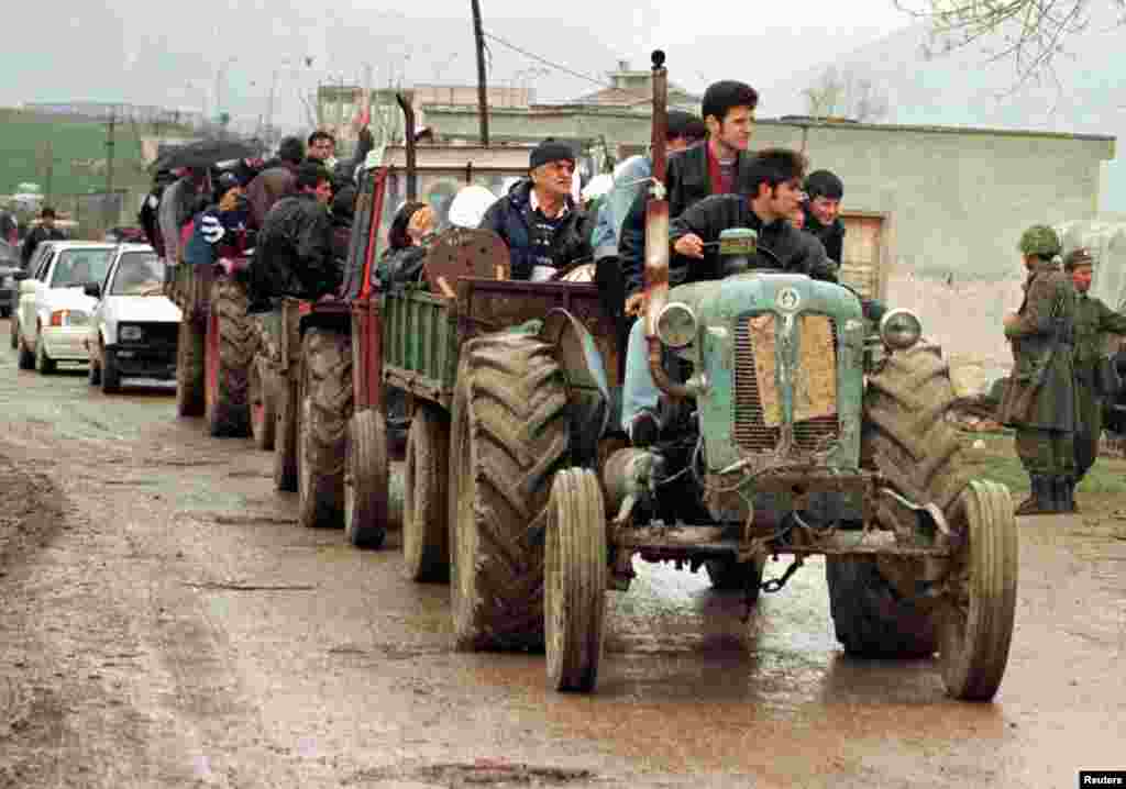 Traktorë të mbushur me refugjatë shqiptarë duke kaluar në Shqipëri, të cilët janë larguar me dhunë nga shtëpitë e tyre nga policë dhe ushtarë serbë, 28 mars 1999. Arben Celi/Reuters.&nbsp; 