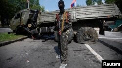 Пророссийский сепаратист стоит рядом с подорванным грузовиком у донецкого аэропорта. 29 мая 2014 года.