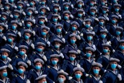 Disa ushtarë me maska përgjatë një parade.