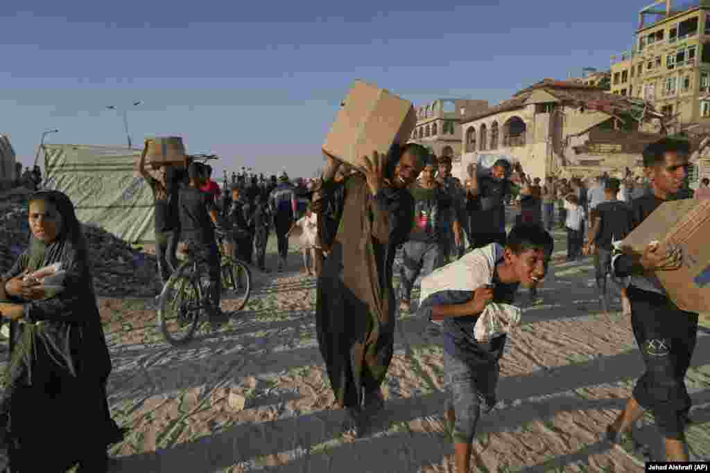 Palestinezë të të gjitha moshave duke bartur pako e thasë me ndihma.