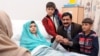 Malala Yousafzai, who was shot in the head by Taliban gunmen for campaigning for the right to an education, sitting on her bed amid her mother Toorpekai Yousufzai (L), brothers Khushal Khan (3rd R) and Apal Khan (R) and father