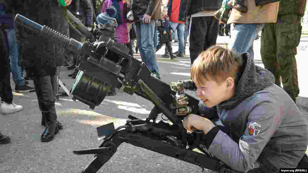 A child looks through the sights of a grenade launcher at an exhibition of Syrian weapons in Sevastopol on April 3.