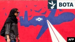 Një grua kalon pranë një murali që përshkruan një mjet ajror pa pilot (dron) të Forcave Ajrore Amerikane, të pikturuar në muret e jashtme të ish-Ambasadës amerikane në Teheran, më 8 prill 2025.
