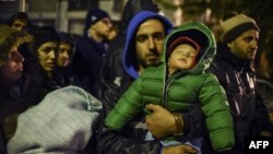 A man carrying his child waits with other migrants and refugees to be registered at a refugee center in Presevo, Serbia, on October 25.