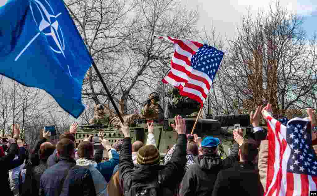 Люди з прапорами США та НАТО вітають військових